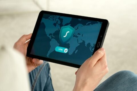 Person holding a tablet that shows a shield icon and a VPN connected switch over a world map