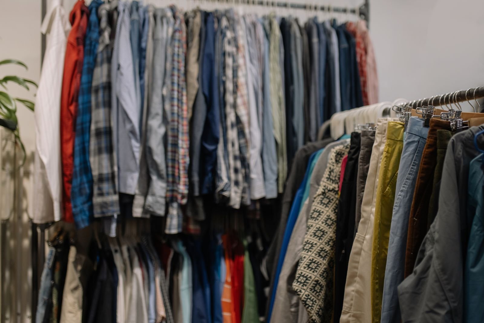 Rack of assorted shirts and jackets in different colors and eras hanging in a thrift shop