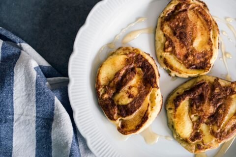 Cinnamon roll pancakes with a brown sugar cinnamon swirl on a white plate