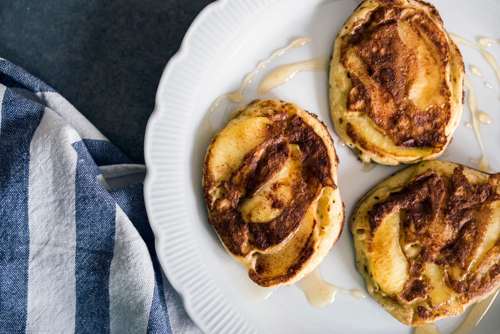 Cinnamon roll pancakes with a brown sugar cinnamon swirl on a white plate
