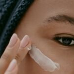 Woman applying a light layer of night cream to her cheek, as in a tretinoin routine