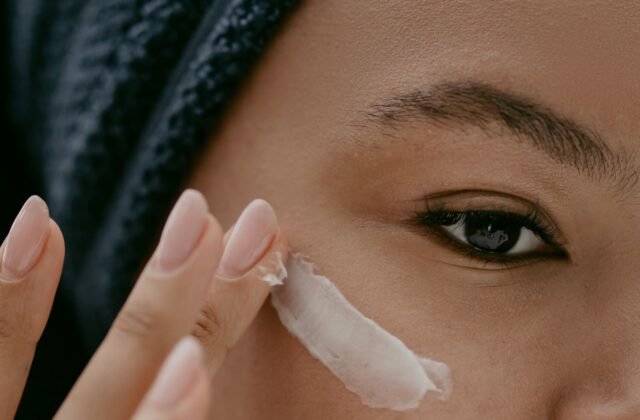 Woman applying a light layer of night cream to her cheek, as in a tretinoin routine