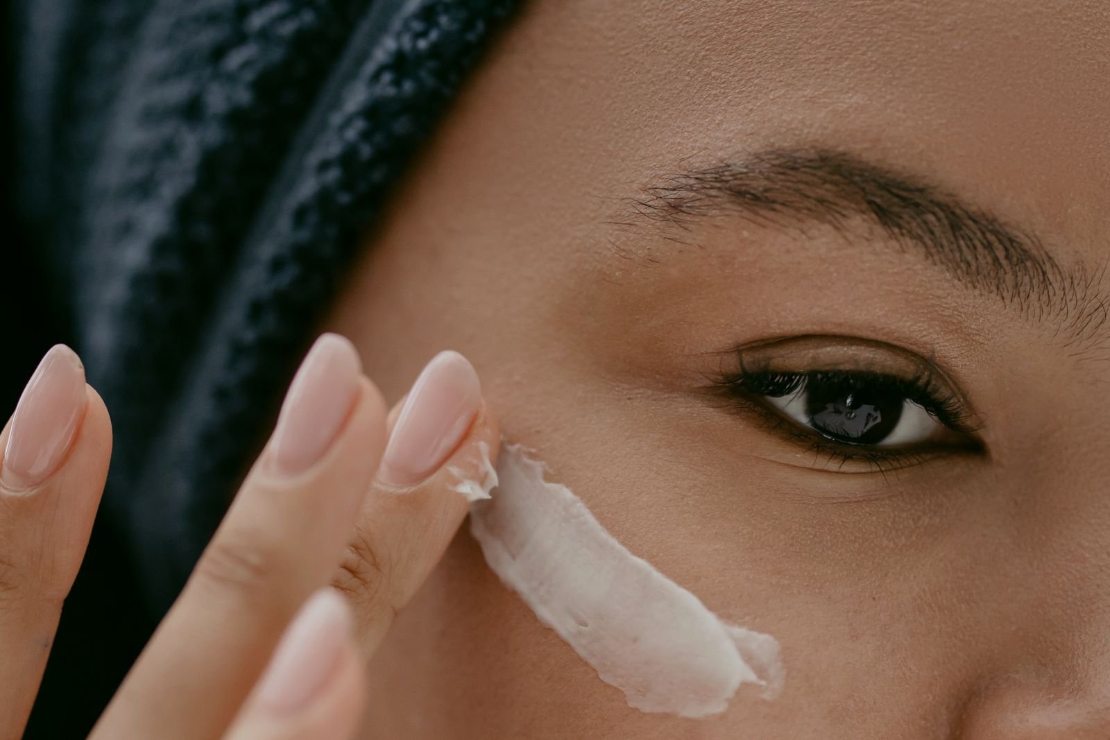 Woman applying a light layer of night cream to her cheek, as in a tretinoin routine